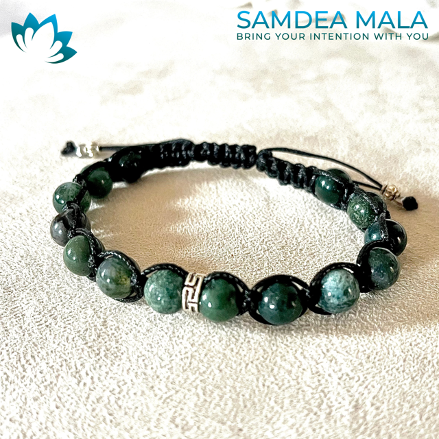 Green moss agate mala bracelet with black cord.  The bracelet features dark green and light green stones and a silver charm. Samdea Mala: Bring Your Intention With You.