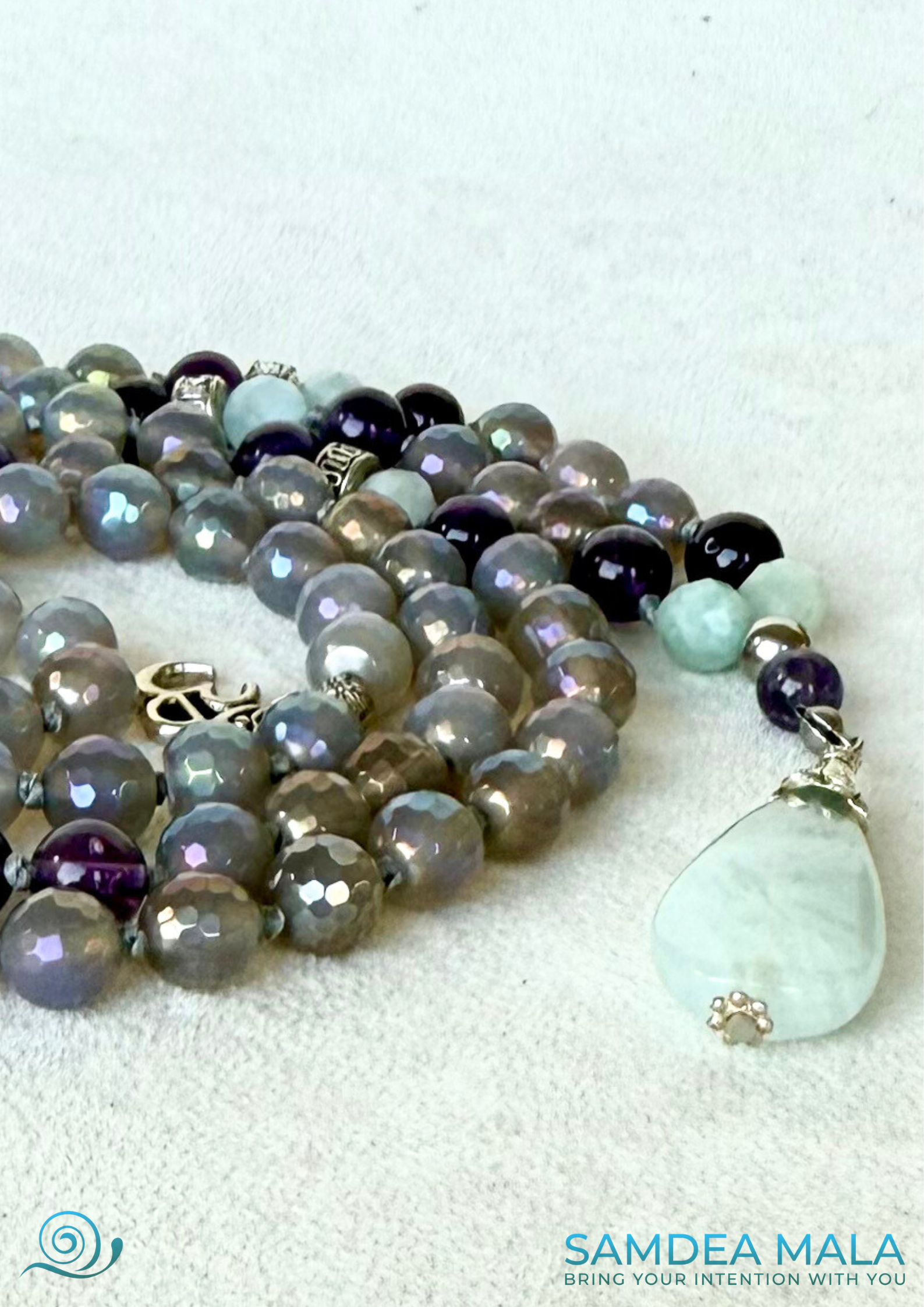 close-up of 108 Samdea Mala, with gray agate and amethyst beads for emotional balance and intuition. Hand-knotted mala necklace rosary with natural aquamarine pendant.