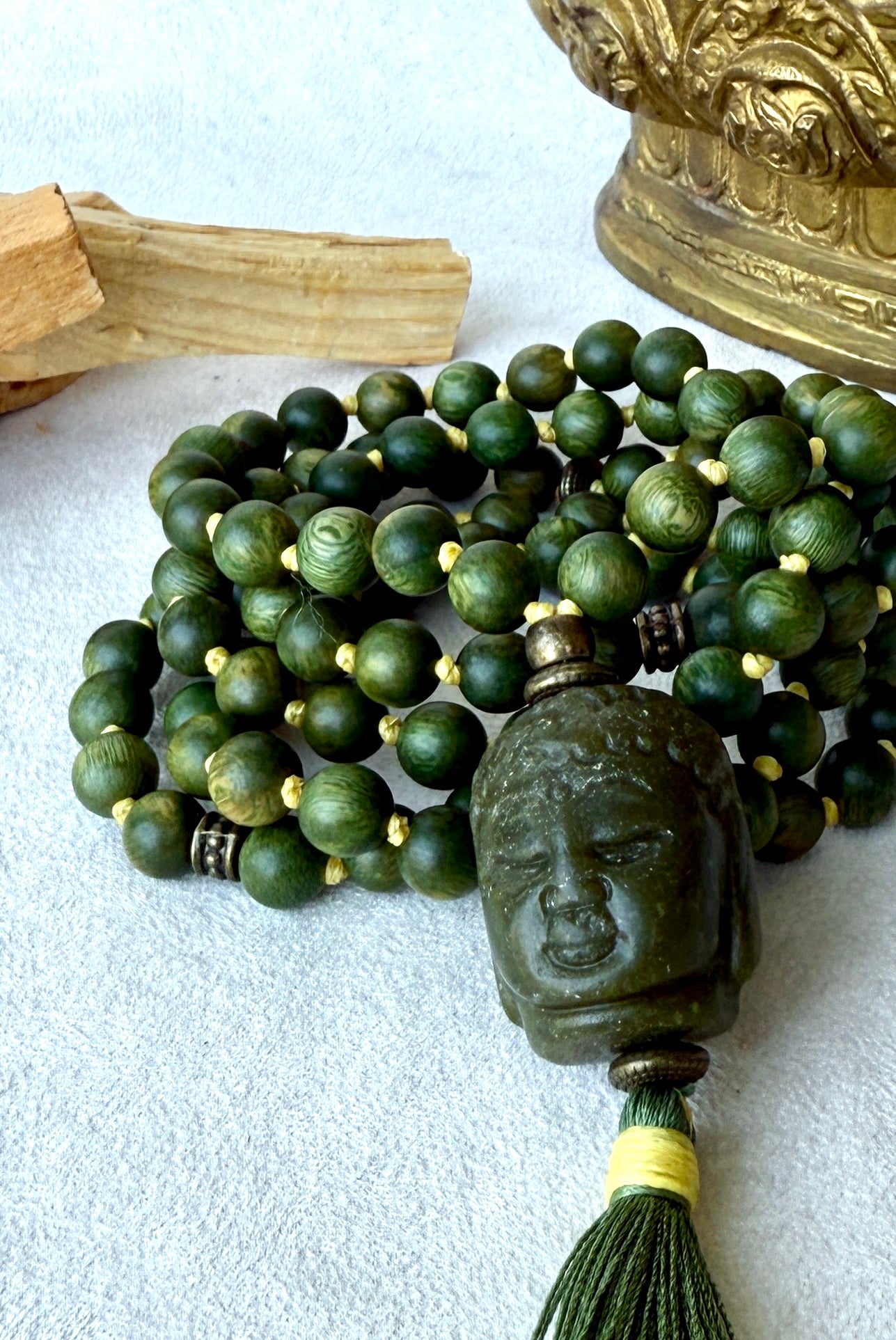 Close-up of Buddha Jade pendant on a natural sandalwood mala beads showing smooth texture and warm brown tones by Samdea mala