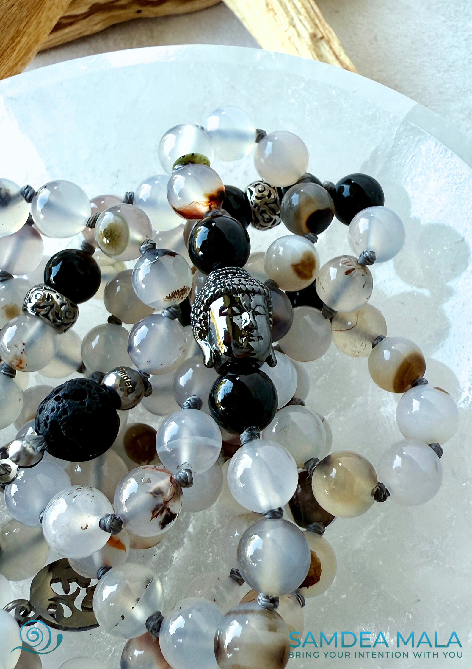 Close-up of Buddha charm. Handmade mala beads necklace in Dendritic Agate, Black Tourmaline, and Lava Stone for protection and balance