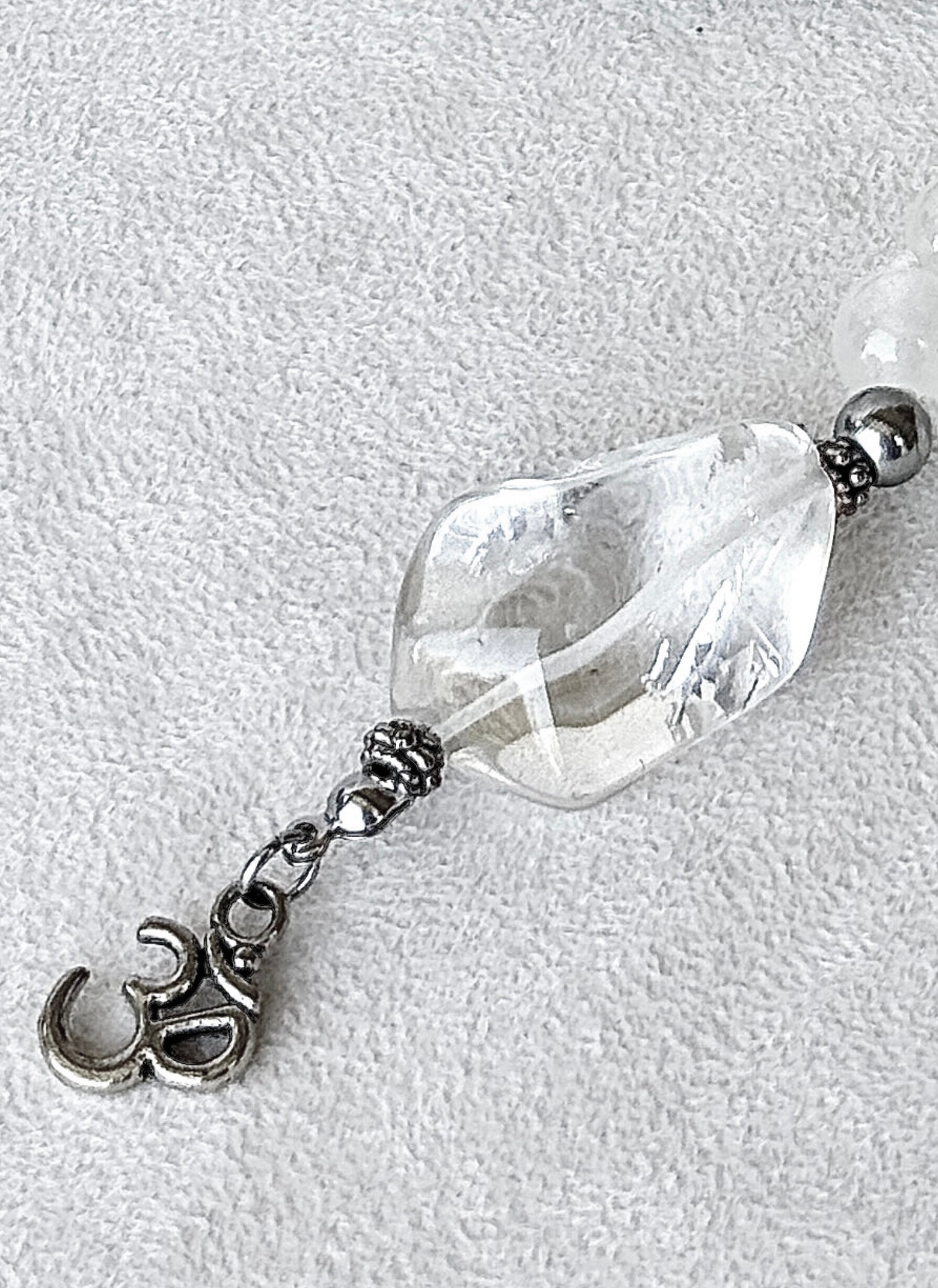 Close-up of Clear Quartz pendant with OM charm in a White Mala for meditation in selenite, labradiorite