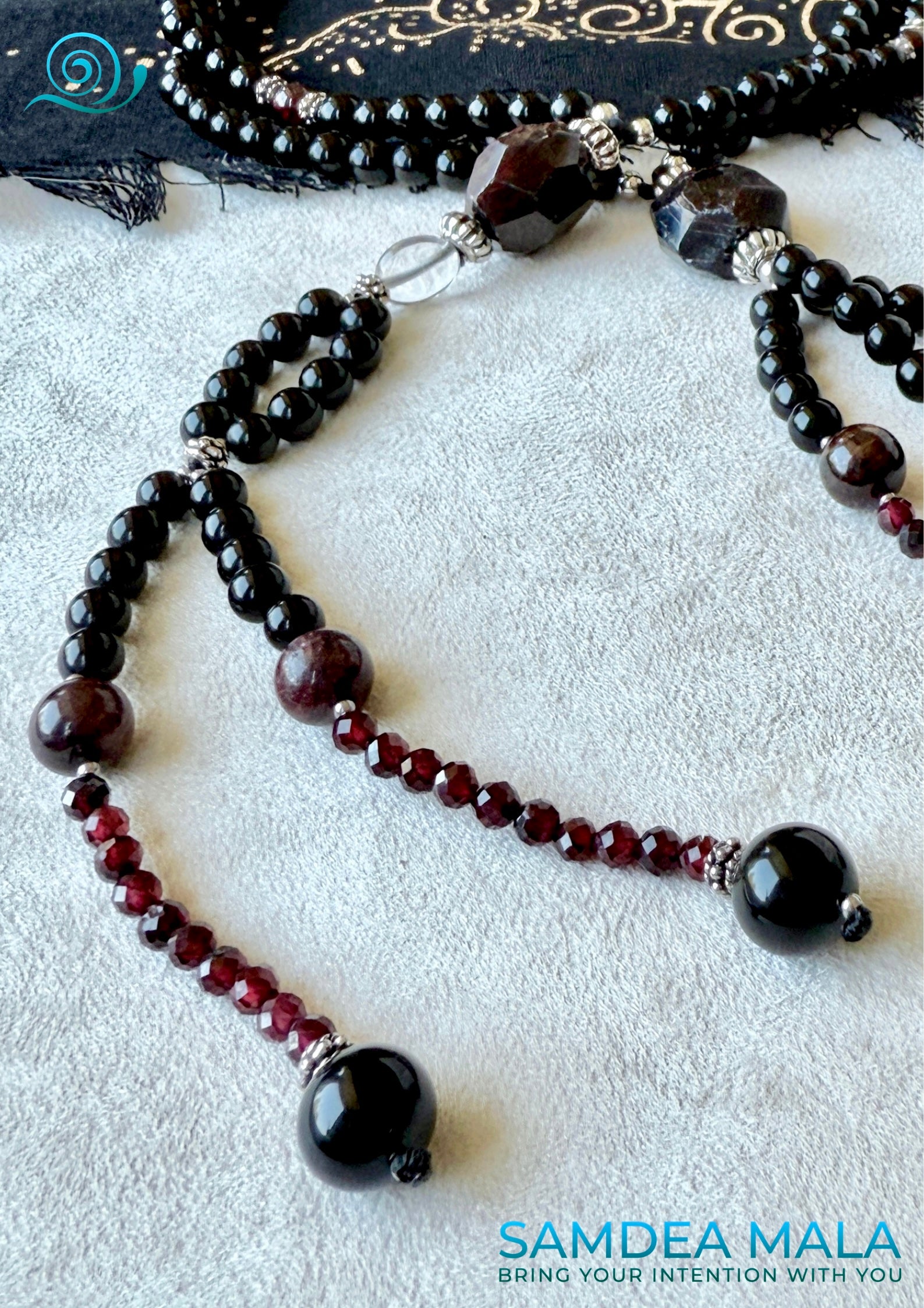 Close-up of handmade obsidian and garnet Buddhist prayer beads – highlighting craftsmanship and deep grounding energy.