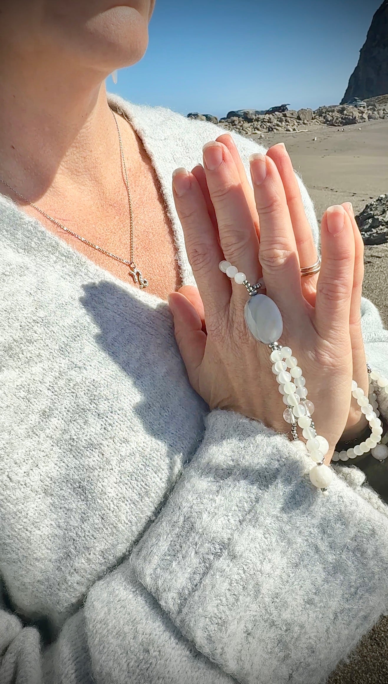Close-up of  hands holding a Nichiren prayer beads with white agate, grey chalcedony, and moonstone. Handcrafted Juzu for chanting Nam Myoho Renge Kyo.
