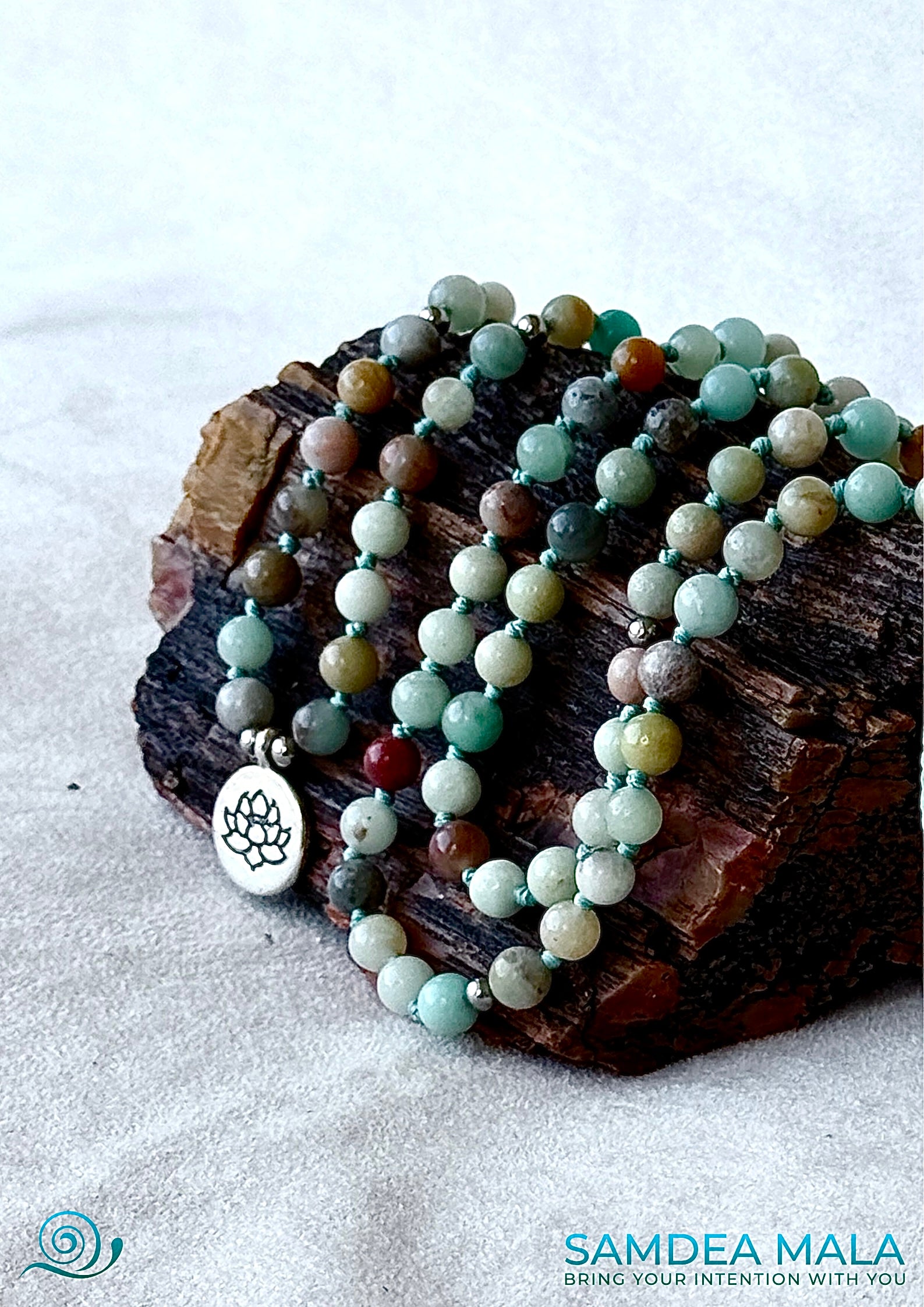Mala and bracelet in Amazonite – handmade spiritual jewelry for meditation, intention, and emotional balance. Custom Tibetan-style mala bracelet with natural gemstones by Samdea Mala. on a petrified wood stone. cclose-up.