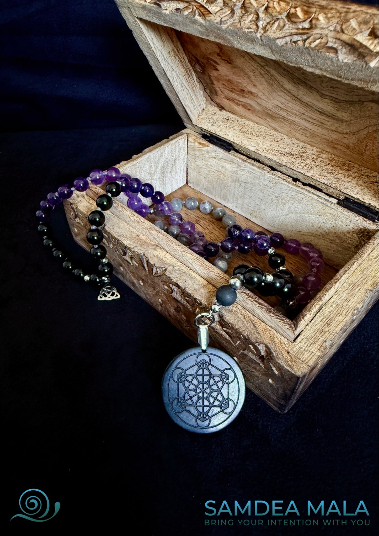 Shadow work mala in an open woodden carve box with om. Obsidian, amethyst, labradorite, and shungite, hand knotted mala, handmade in US. 108 grounding meditation beads with dark feminine spiritual energy. Inner child and trauma healing mala necklace.