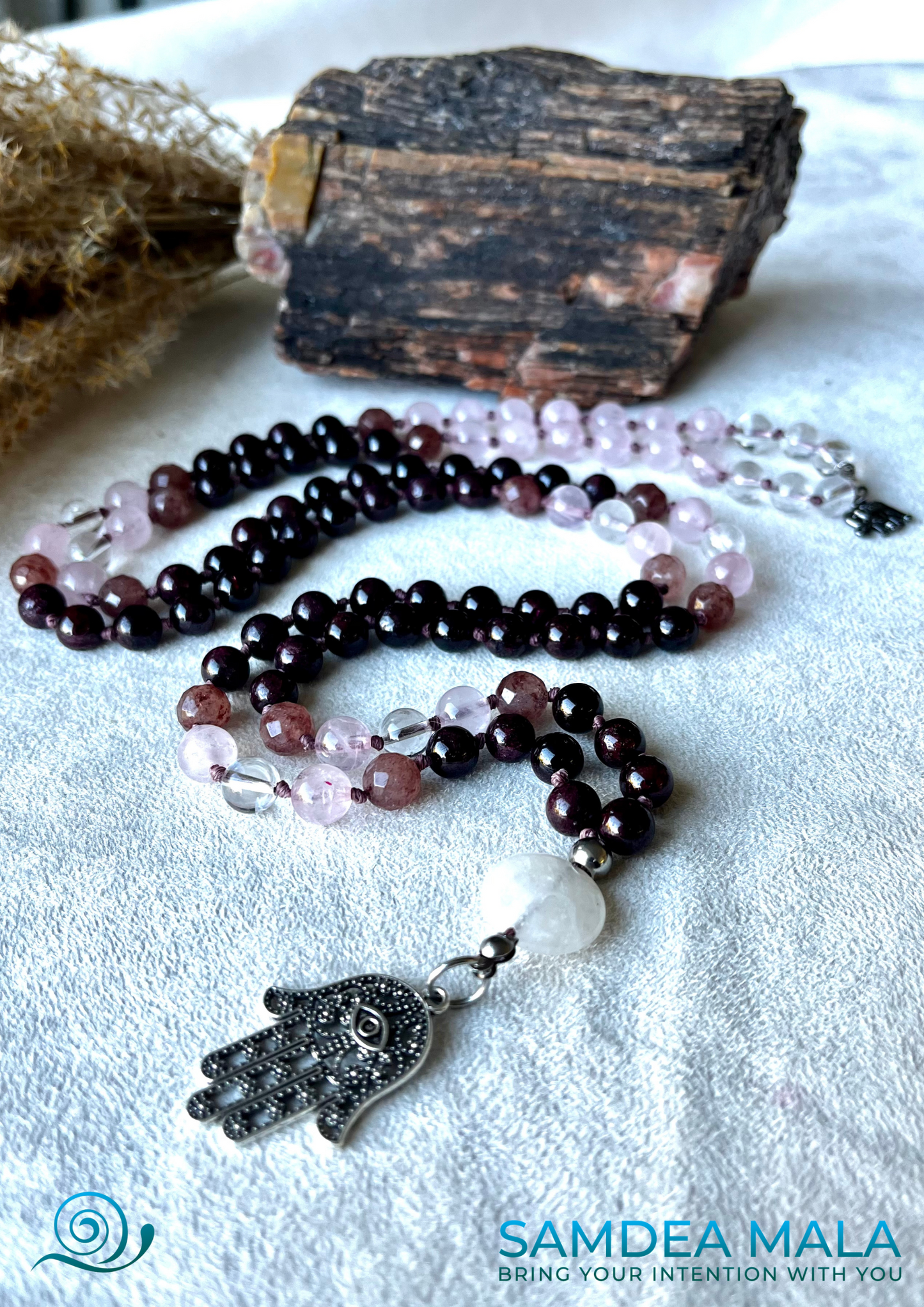 Personalized holistic jewelry — mala beads for mindfulness in garnet, rose quartz, and clear quartz, with a Hamsa hand pendant.