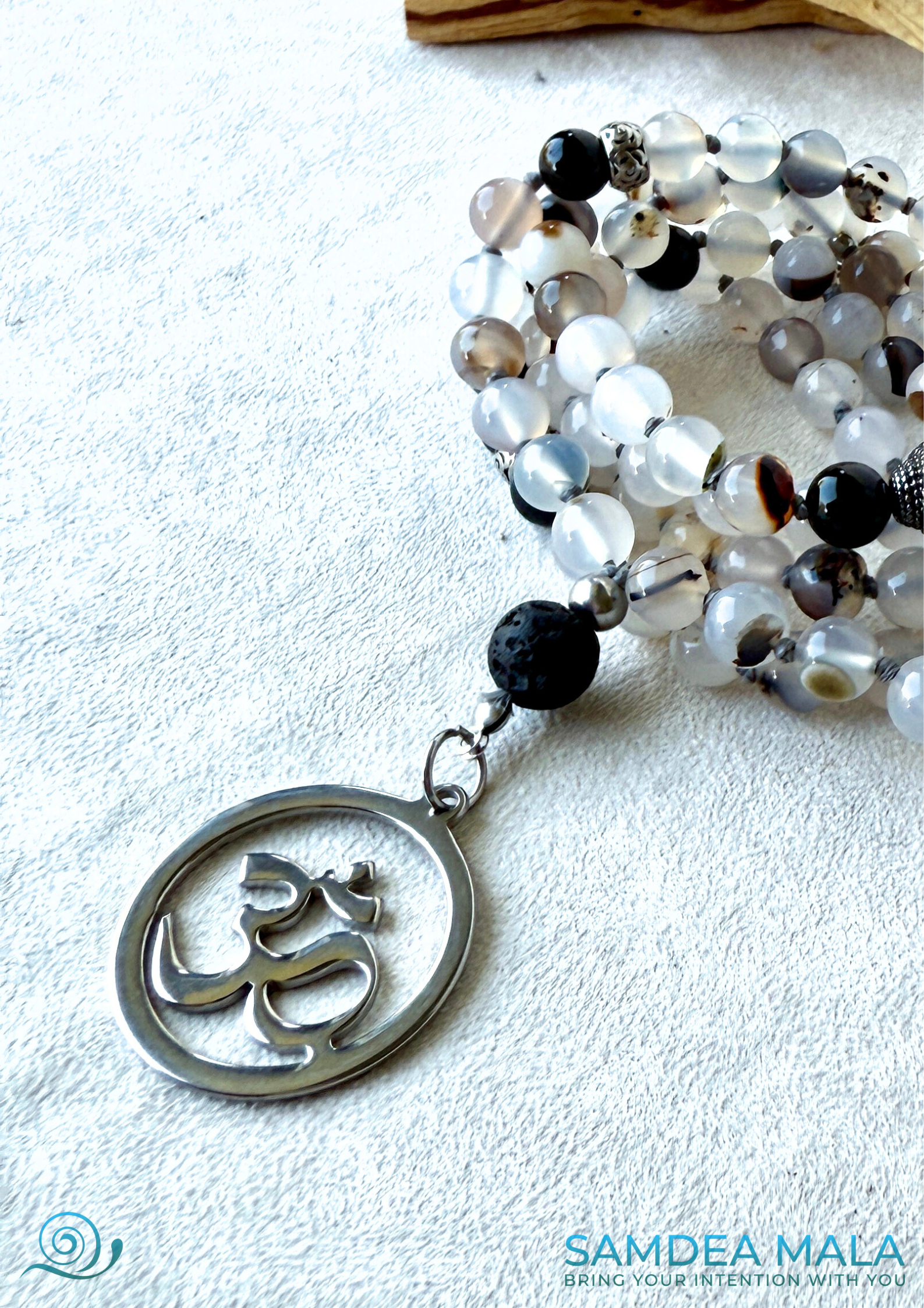 Close-up of Om pendant. Handmade mala beads necklace in Dendritic Agate, Black Tourmaline, and Lava Stone for protection and balance