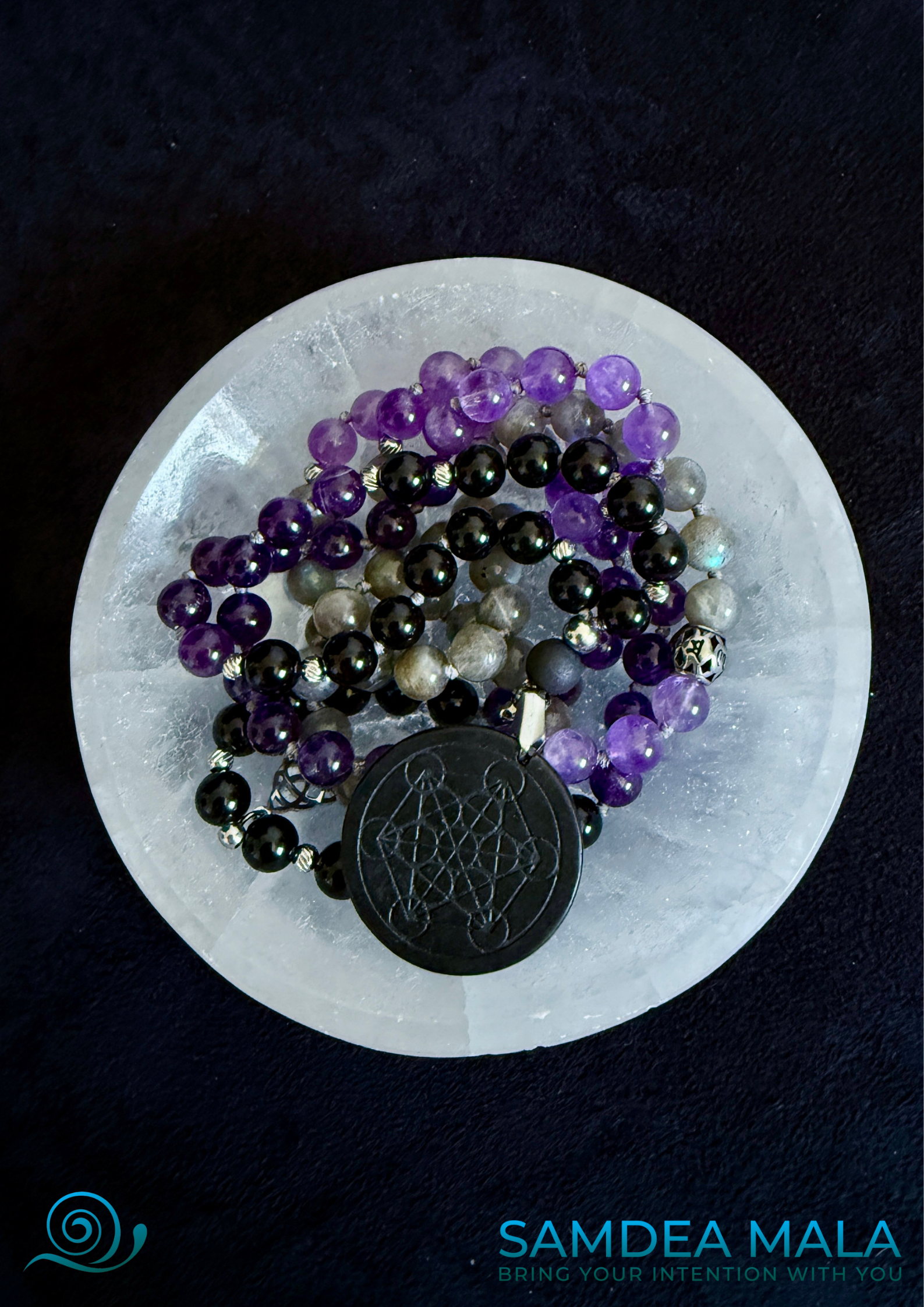 Shadow work mala on a selenite bowl. Obsidian, amethyst, labradorite and shungite, hand knotted mala, handmade in US. 108 grounding meditation beads with dark feminine spiritual energy. Inner child and trauma healing mala.