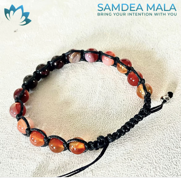 Mala bracelet Shamballa Tibetan featuring natural gemstones: carnelian and dark red gemstone beads on a black cord.  The bracelet has a sliding knot closure and a mix of red, orange, and deep red beads.