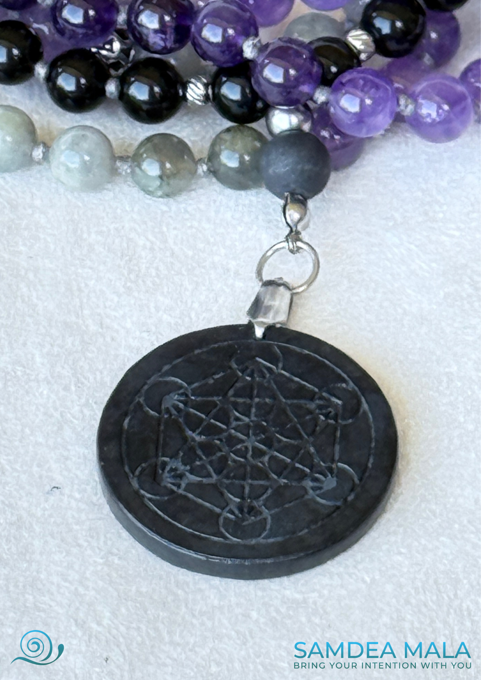 Close- up of Shungite Pendant engraved with Metatron’s Cube, a powerful symbol of sacred order and deep energetic protection. Samdea Mala for shadow work with obsidian, amethyst, and labradorite, hand knotted mala, handmade in US. 108 grounding meditation beads with dark feminine spiritual energy. Inner child and trauma healing mala