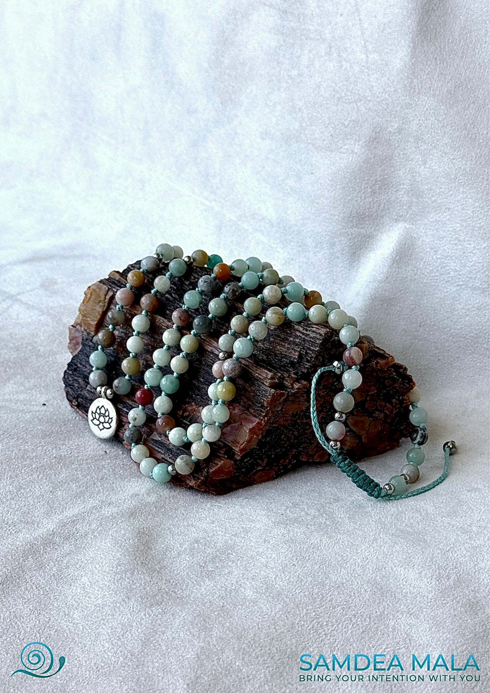 Spiritual Mala necklace and bracelet in Amazonite with natural gemstones with a lotus charm for meditation and mindfulness on a petrified wood stone.