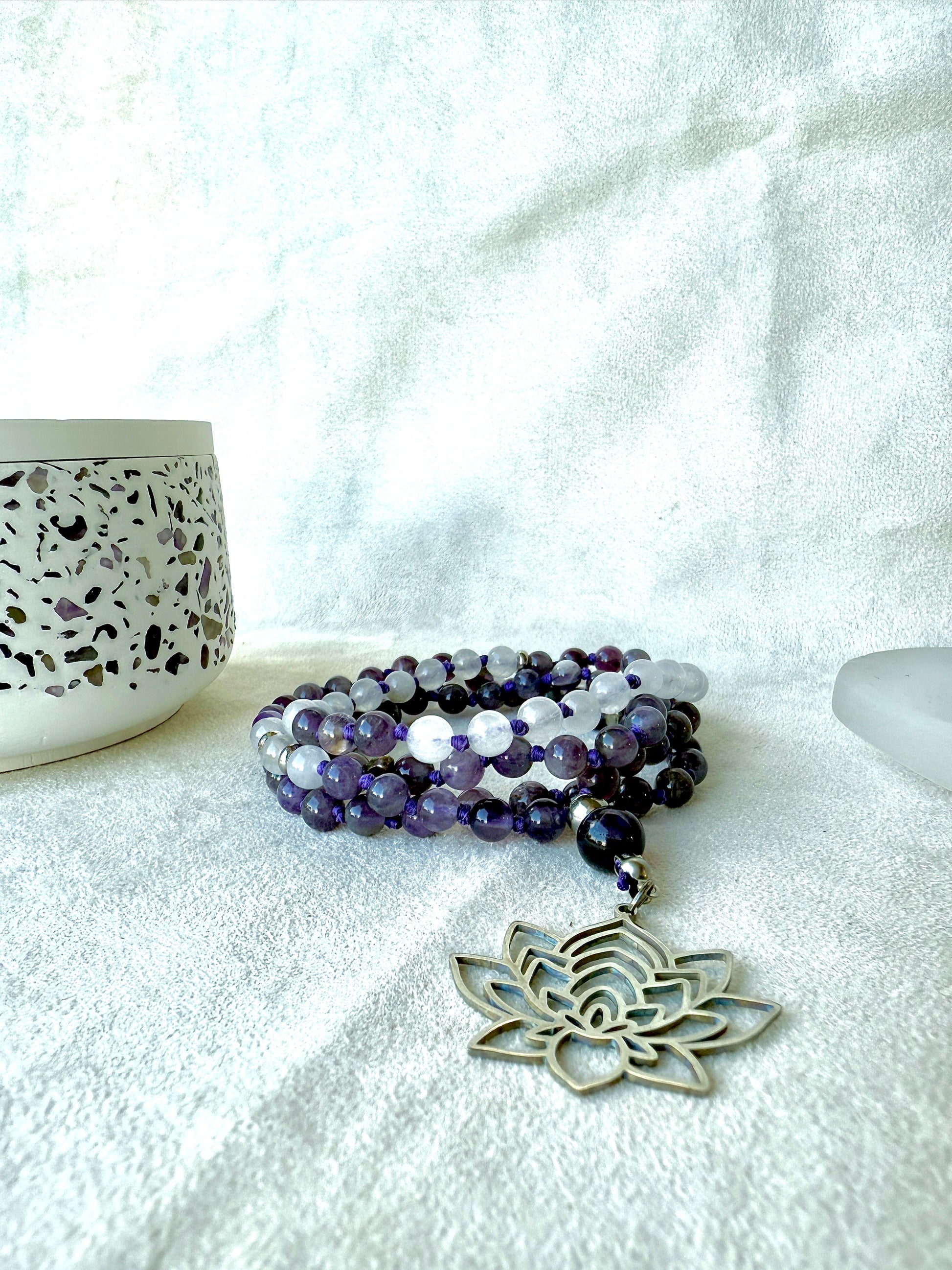 White jade and amethyst mala beads coiled on altar, spiritual jewelry for mindfulness