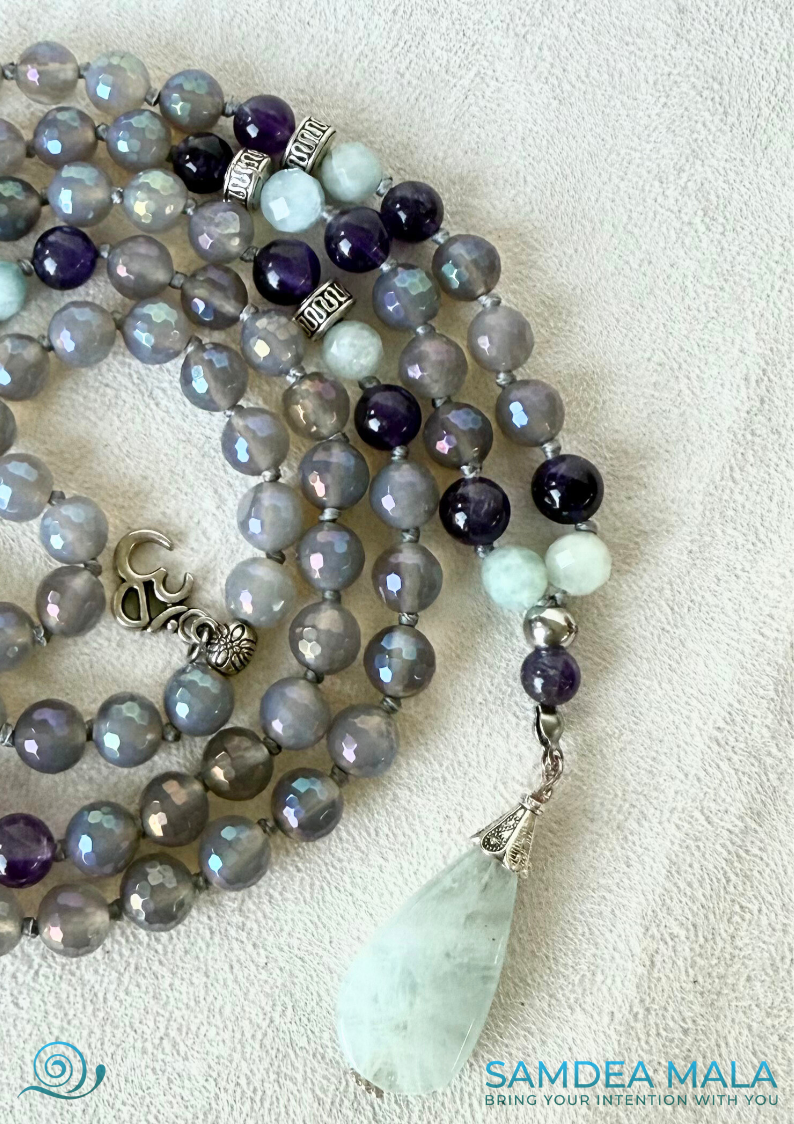 close-up of 108 Samdea Mala, with gray agate and amethyst beads for emotional balance and intuition. Hand-knotted mala necklace rosary with natural aquamarine pendant.