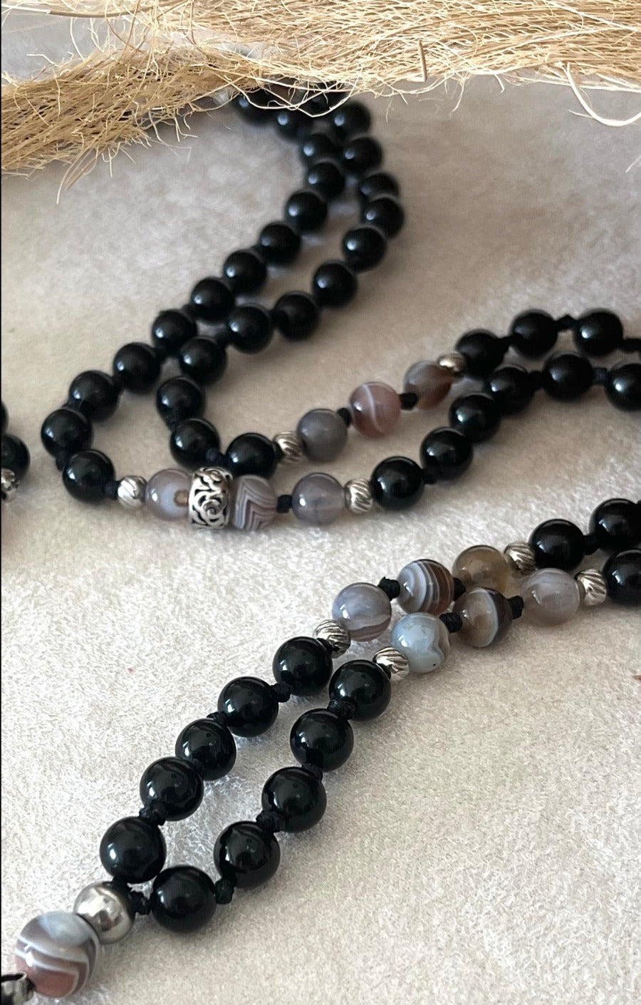 close up of Hand-knotted Obsidian and Botswana Agate mala with Buddha pendant for meditation and protection by Samdea Mala