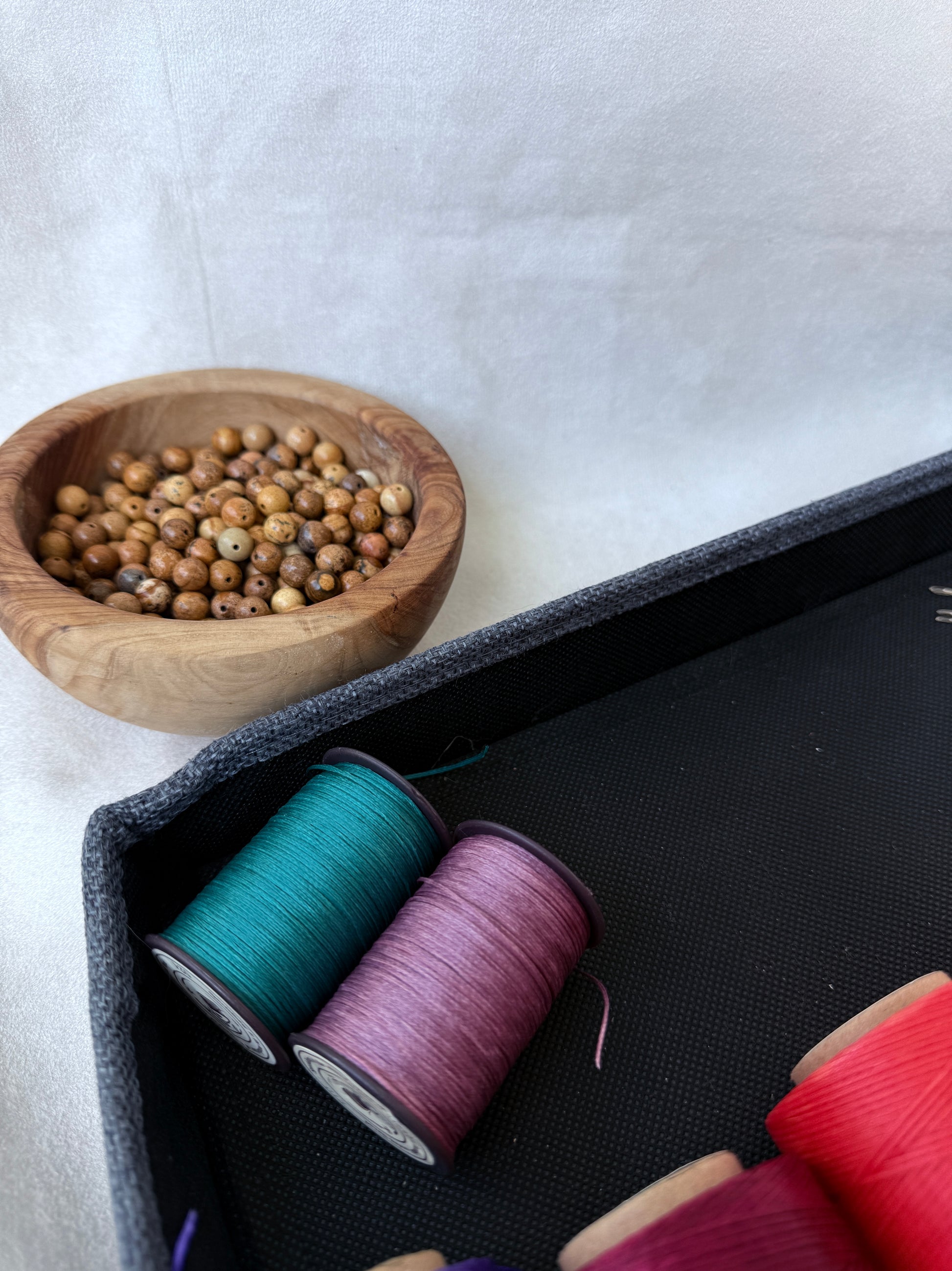 DIY thread and needle kit. Mala crafting tools: spool of flat thread with beading needles. DIY mala making materials. Large-eye and standard beading needles for mala repair. Handmade mala repair kit with calm spiritual setup.