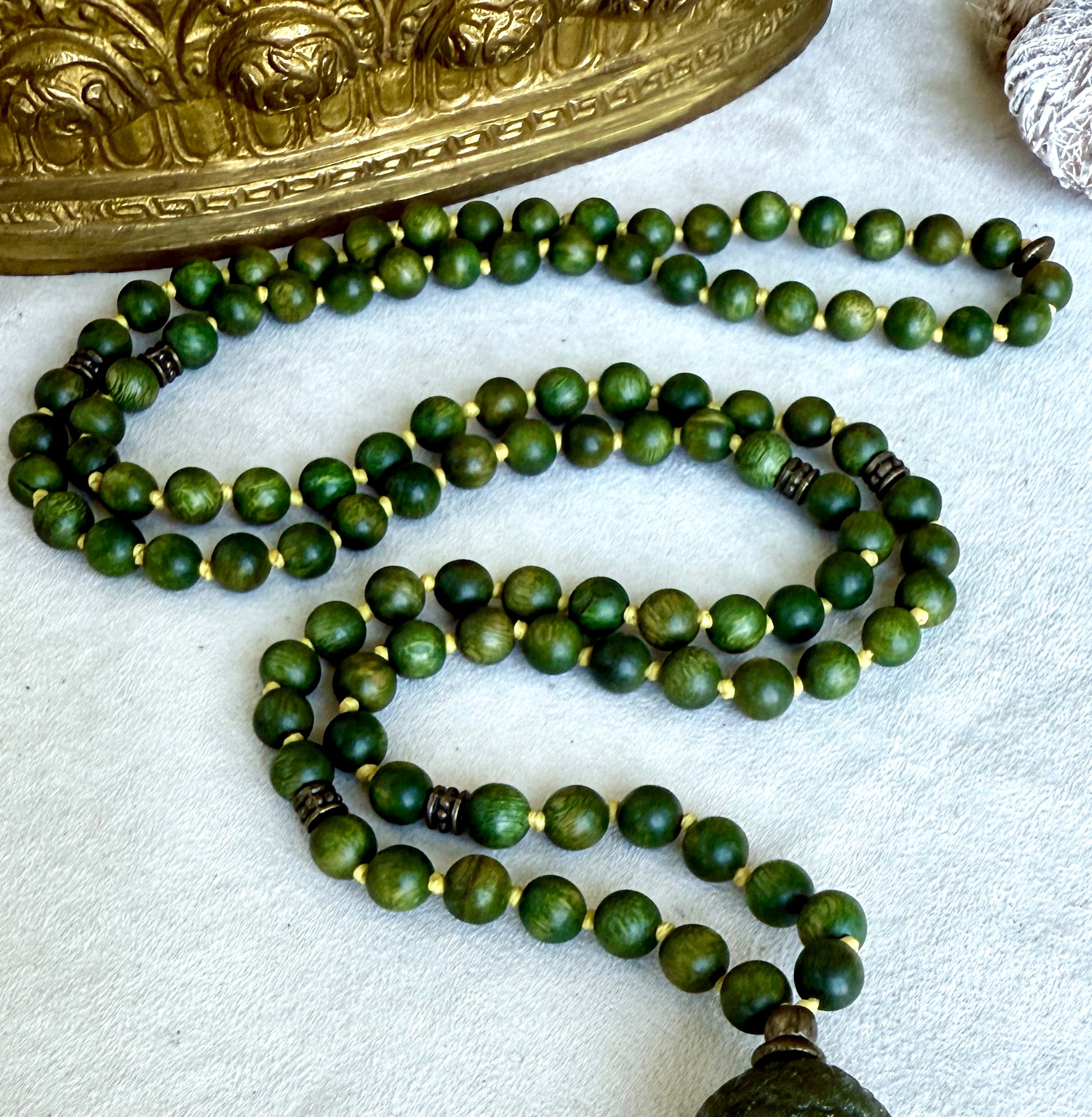 Close-up of natural sandalwood mala beads showing smooth texture and warm brown green tones