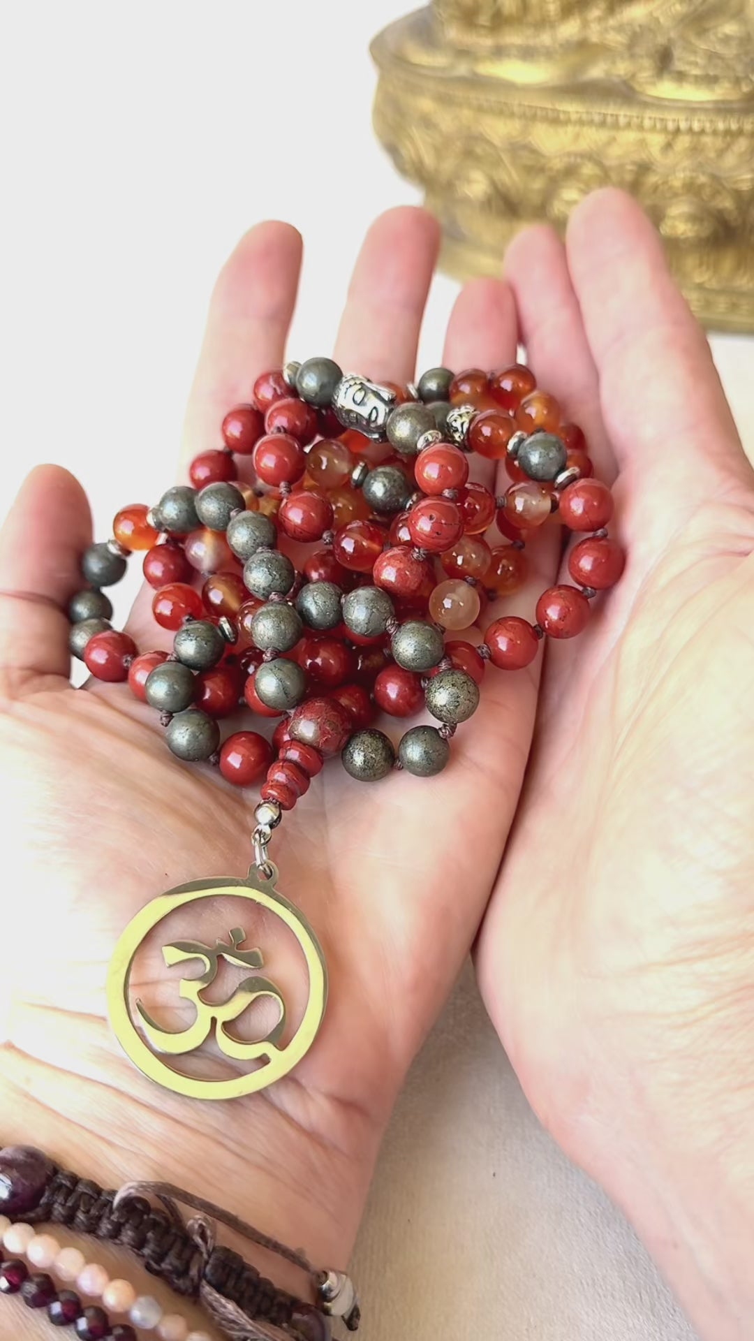 Video preview of Grounding Mala Necklace – Red Jasper, Carnelian, Pyrite | 108 Beads for Courage, Vitality & Inner Strength | Root Chakra Mala - zodiac sign Aries, detail of OM pendant