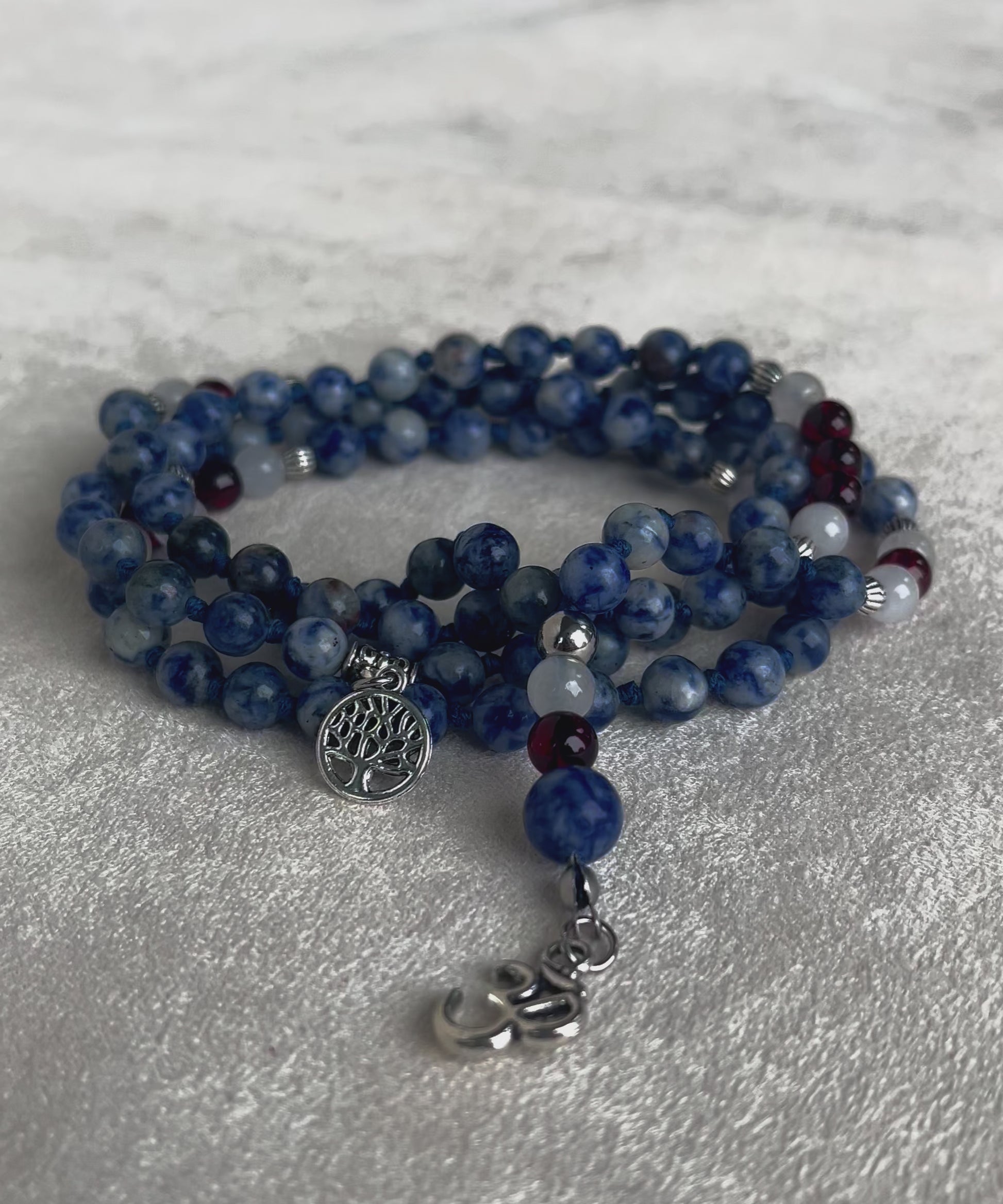 video preview of Blue Mala necklace in Jasper, White Jade & Garnet – Handmade Meditation Necklace with om pendant and tree of life charm