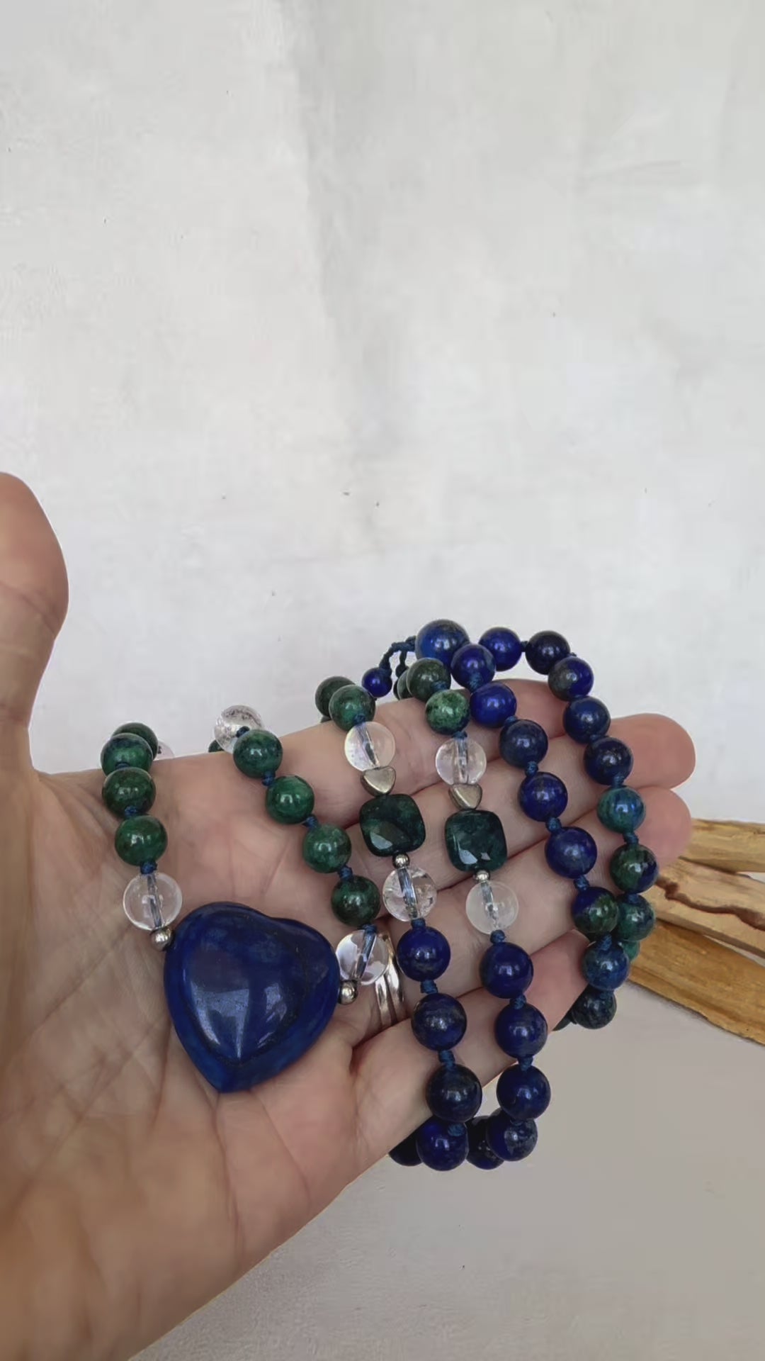 Video frame showing mala gently turning, heart Meru sparkling in light, Samdea Mala in chrysocolla, lapis lazuli and quartz with heart-shaped Meru