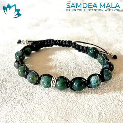 Green moss agate mala bracelet with black cord.  The bracelet features dark green and light green stones and a silver charm. Samdea Mala: Bring Your Intention With You.