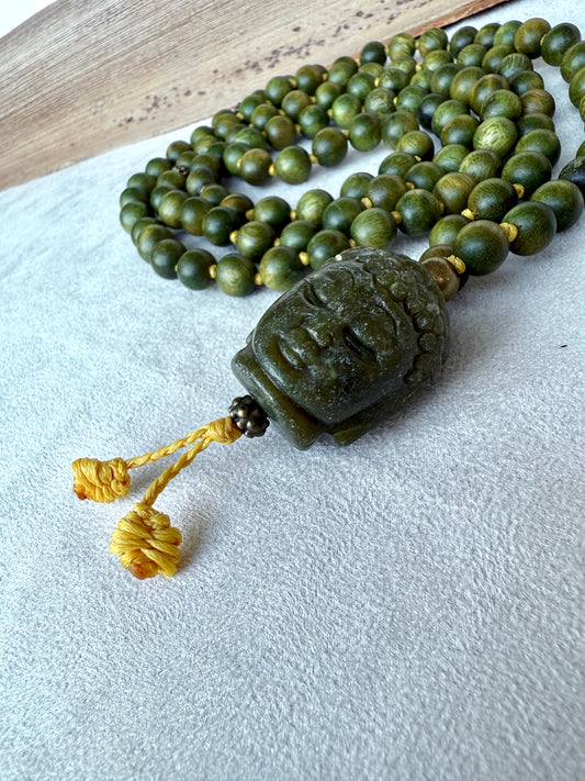 Close-up of Buddha Jade pendant on a natural sandalwood mala beads showing smooth texture and warm brown tones by Samdea mala