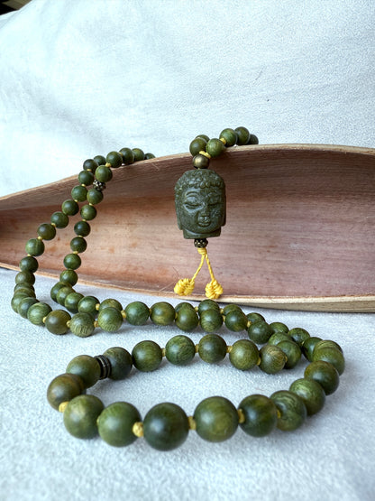 Close-up of Buddha Jade pendant on a natural sandalwood mala beads showing smooth texture and warm brown tones
