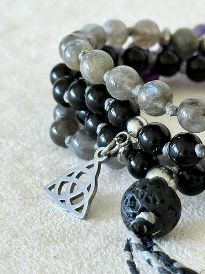 Close-up detail of labradorite and obsidian beads on the Shadow Work Mini Mala, with silver Triquetra charm and lava stone meru bead.