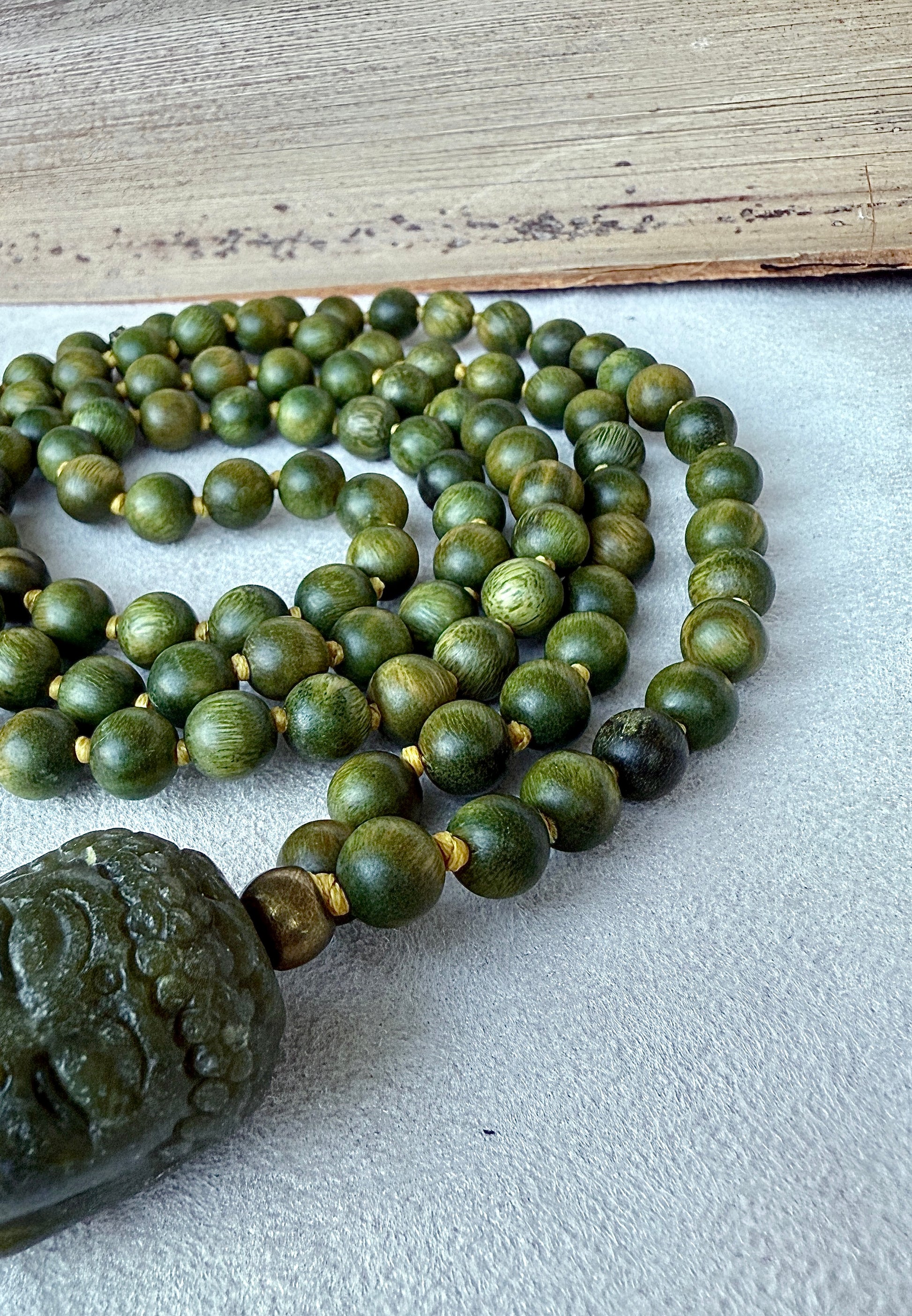 Close-up of natural sandalwood mala beads showing smooth texture and warm brown green tones