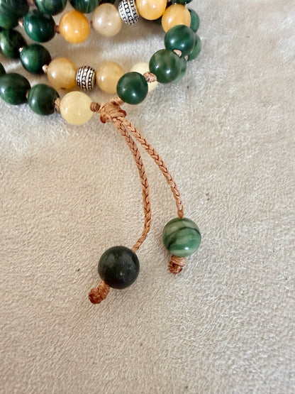 Close up of a short green mala necklace coiled to show 31.5 inch length and Ganesha pendant for abundance 