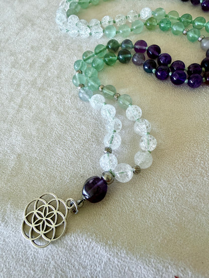 Detail of seed of life on a Natural Green fluorite, amethyst and clear quartz mala necklace for meditation and spiritual practice, Hand-knotted 108 bead mala with natural untreated gemstones and amethyst meru bead