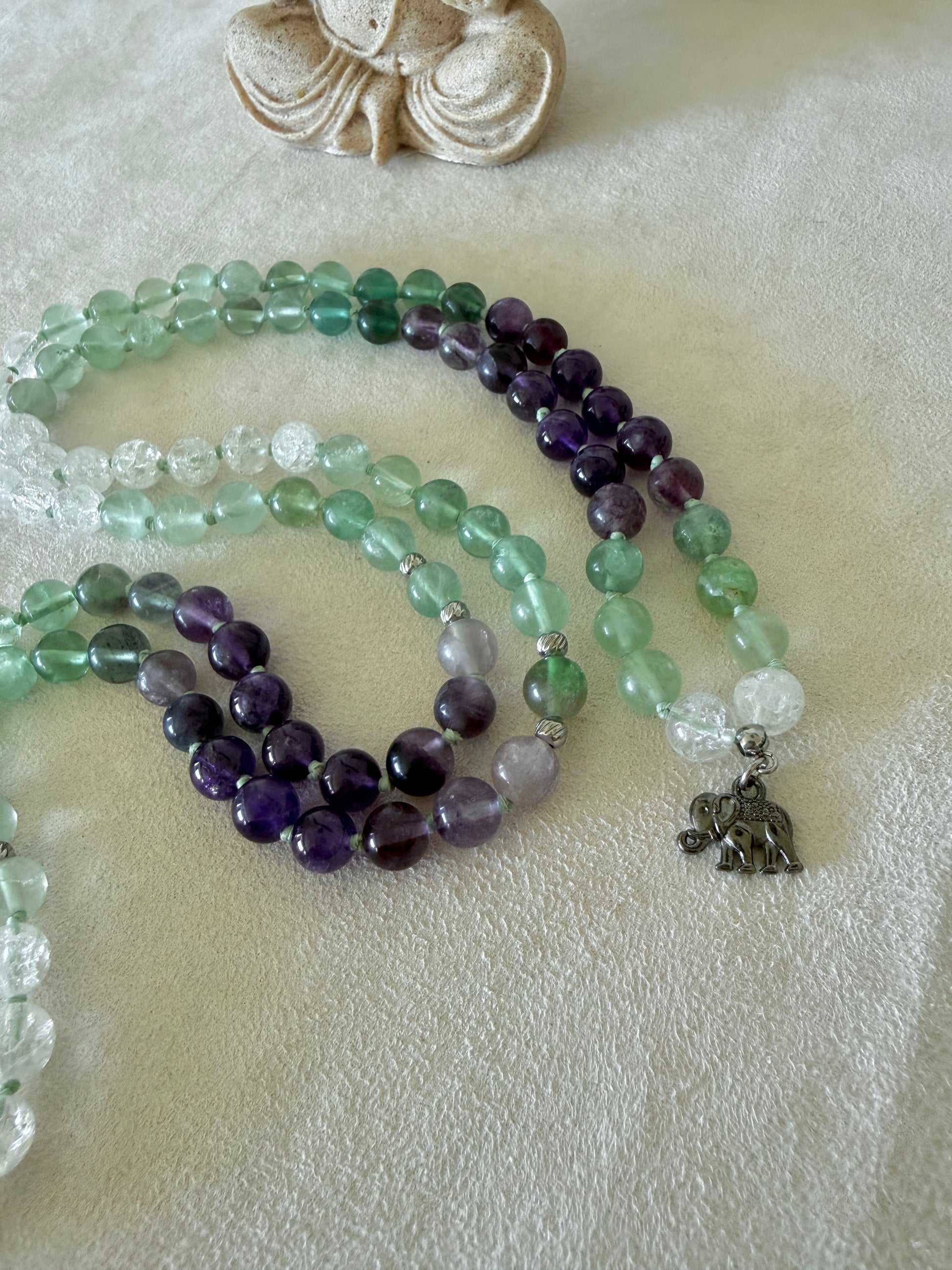 Detail of small elephant charm on a Natural Green fluorite, amethyst and clear quartz mala necklace for meditation and spiritual practice, Hand-knotted 108 bead mala with natural untreated gemstones and amethyst meru bead