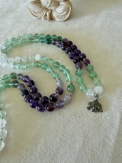Detail of small elephant charm on a Natural Green fluorite, amethyst and clear quartz mala necklace for meditation and spiritual practice, Hand-knotted 108 bead mala with natural untreated gemstones and amethyst meru bead