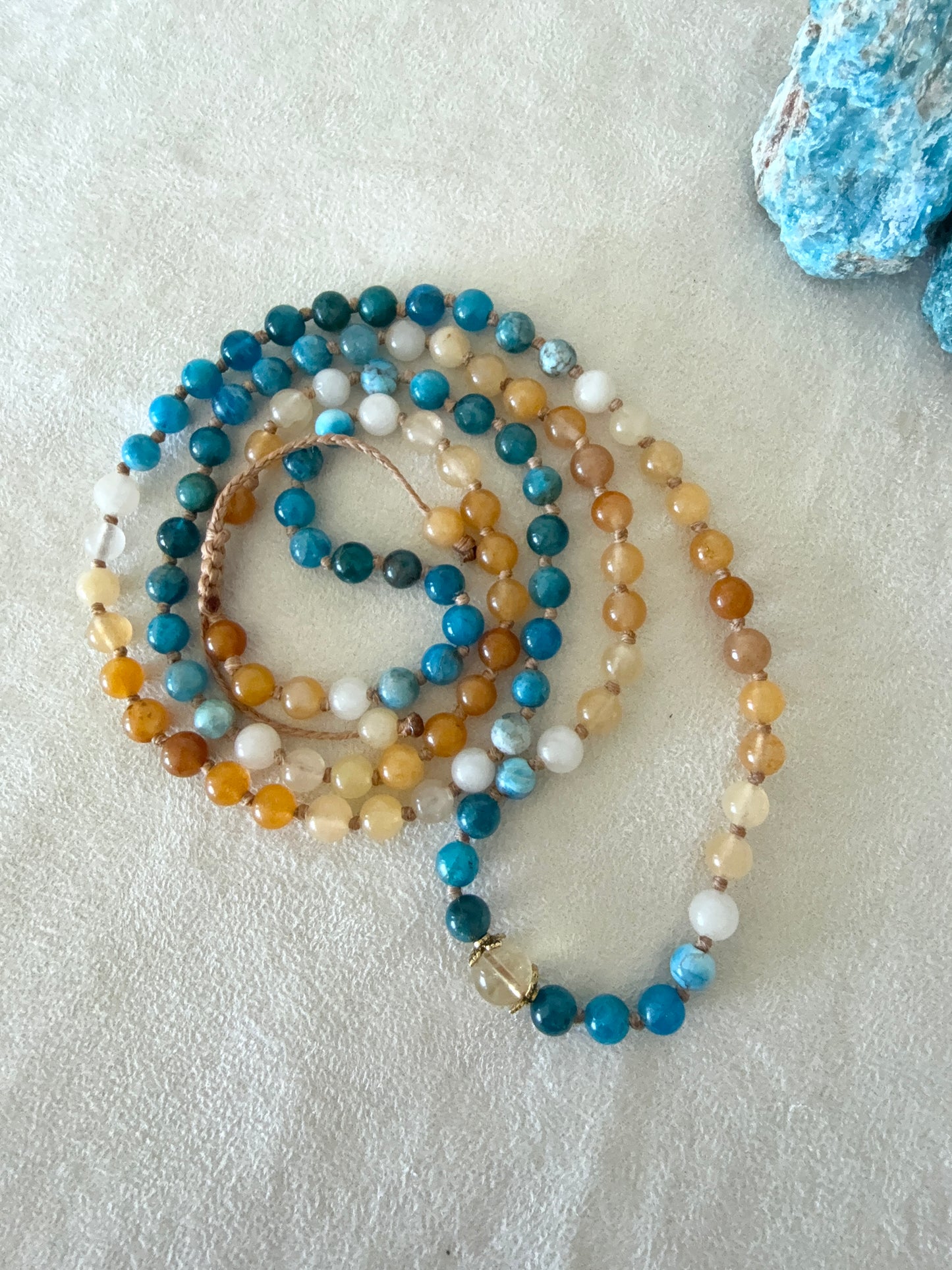 Full view fo The Sun and the sea natural gemstone mala bracelet. Handmade Apatite and Yellow Jade mala bracelet with natural 6 mm gemstones, Citrine guru bead, adjustable macramé closure, and stainless steel details; a 108 bead mala necklace inspired by sea and sun, water and fire, for meditation, yoga, and intention practice.