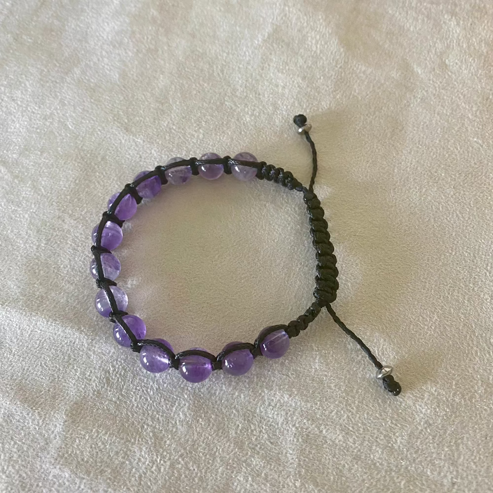 Full view of a purple amethyst gemstone bracelet with black cord and silver metal beads. Shamballa spiritual bracelet by Samdea