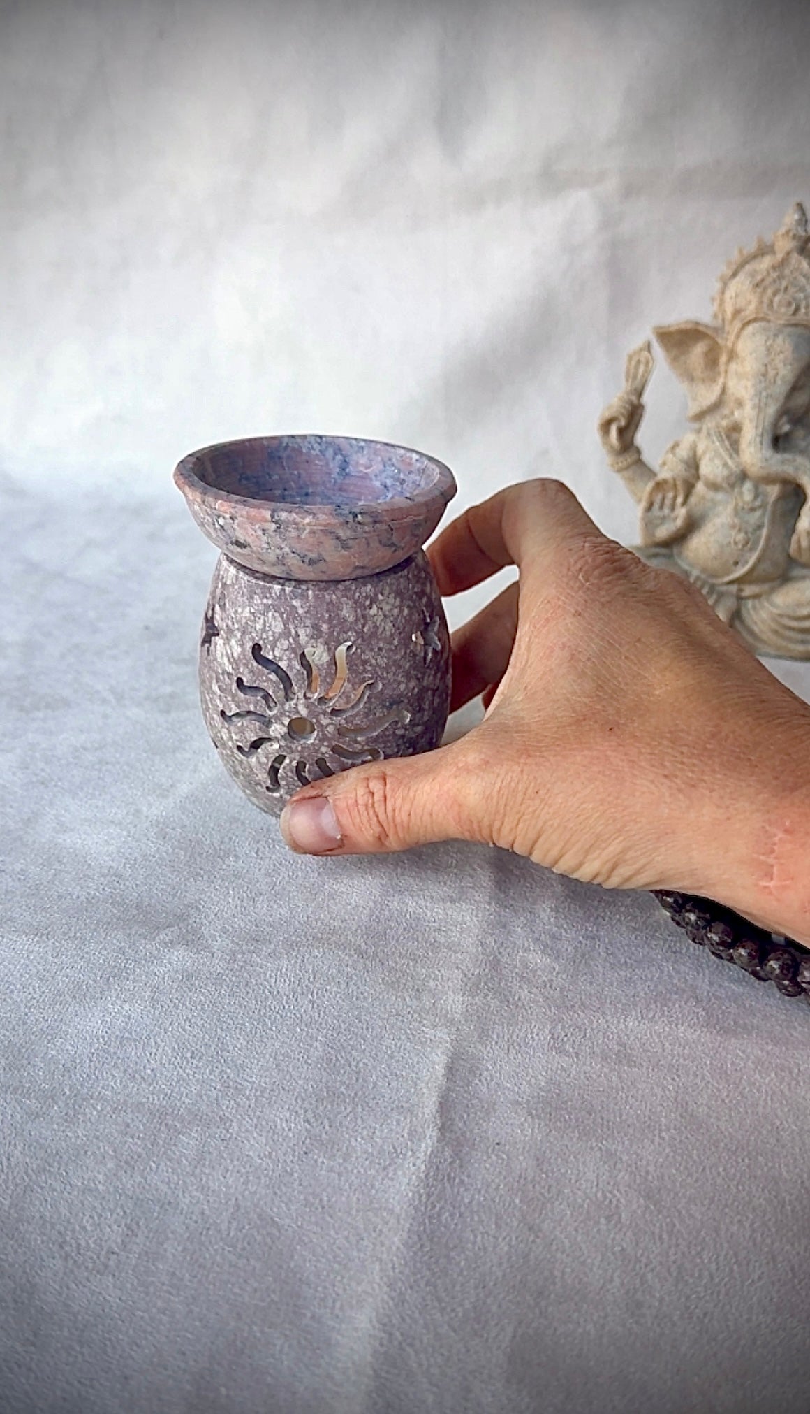 Hand holding carved soapstone burner, tactile natural stone for mindful rituals