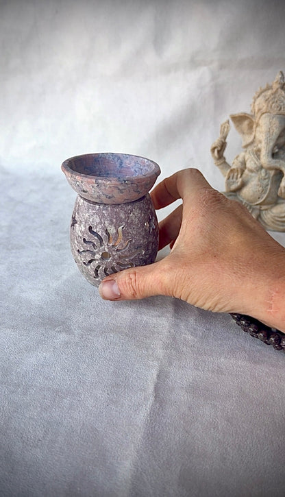 Hand holding carved soapstone burner, tactile natural stone for mindful rituals