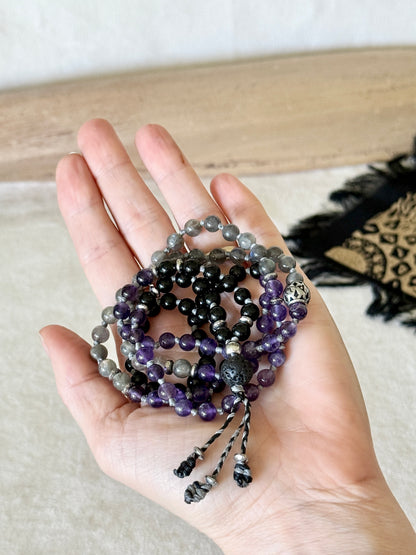 Hand holding the coiled Shadow Work Mini Mala, showing the scale of the 6mm obsidian, amethyst, and labradorite beads