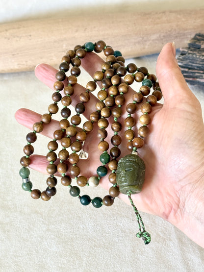 Handmade sandalwood and Indian agate mala draped over a hand, with jade Buddha pendant