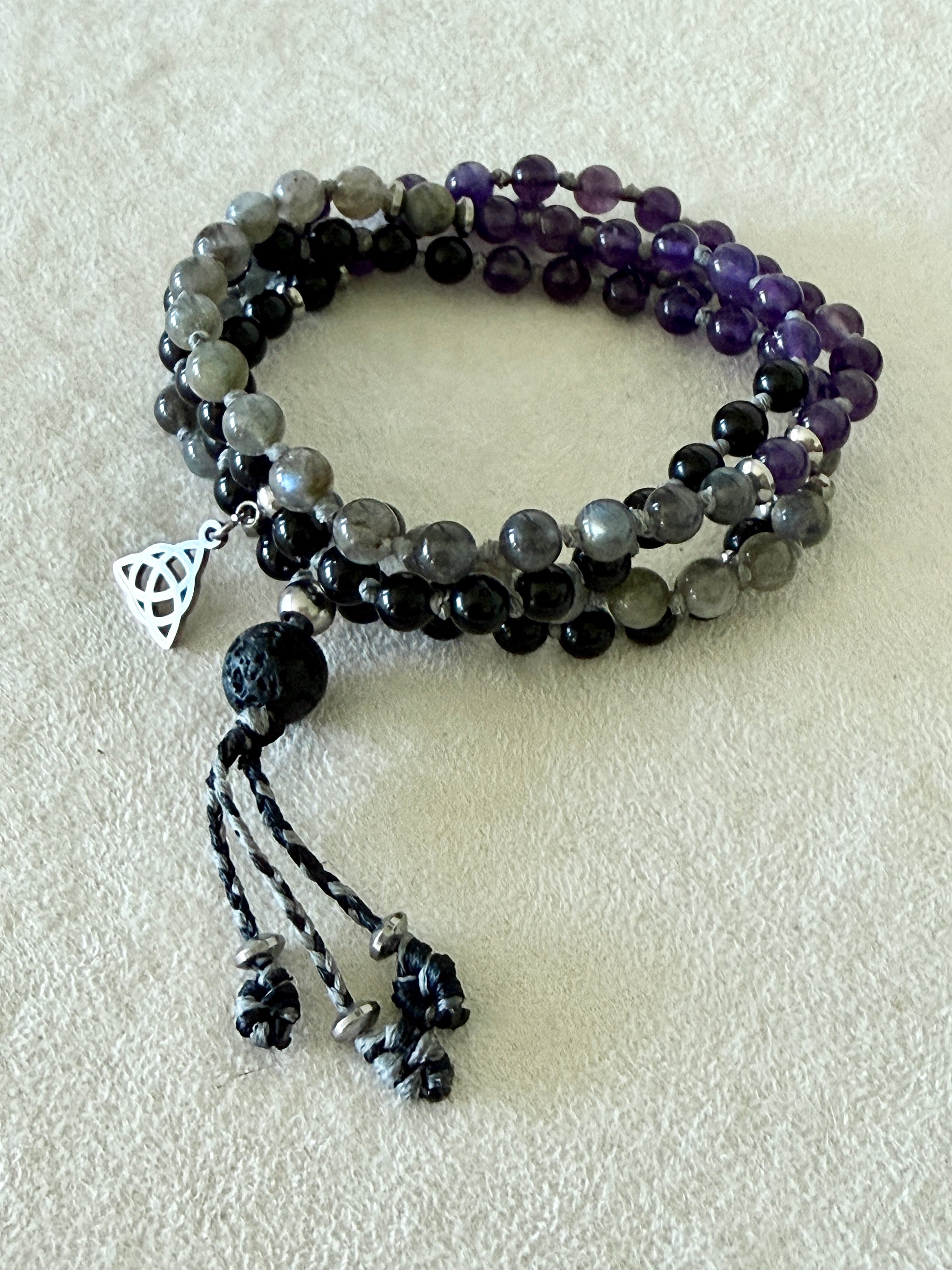 Top-down flat lay of the coiled Shadow Work Mini Mala, showing the alternating obsidian, amethyst, and labradorite bead pattern.
