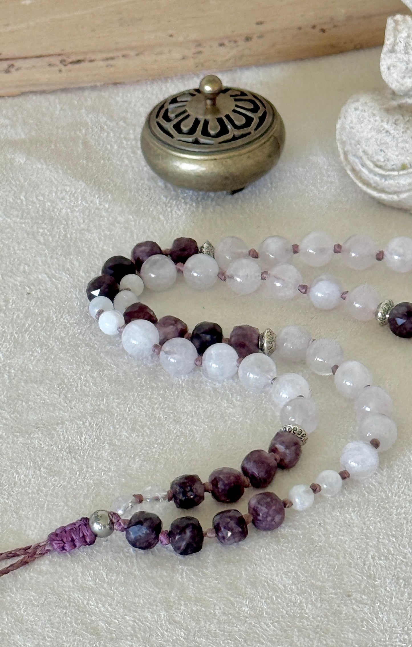 Detail of the Pause Breathing Mala strand, showing the graduated garnet, clear quartz, and rose quartz beads
