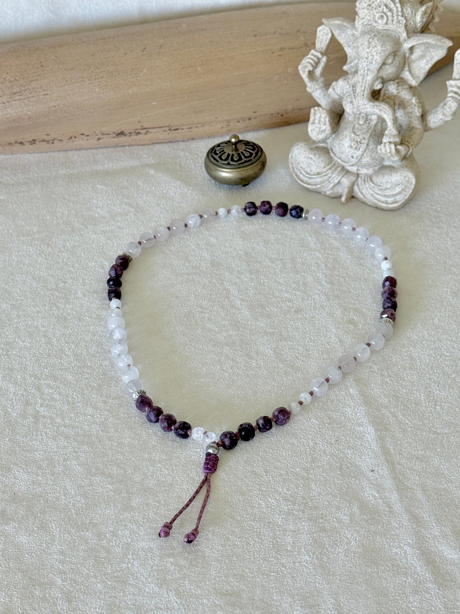 Pause Breathing Mala bracelet laid in a circle beside a Ganesha statue, for mindful breathing practice