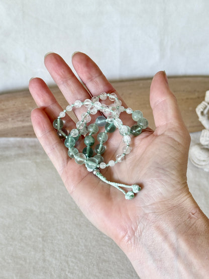 Bracciale mezzo mala Pause Breathing appoggiato su un palmo aperto, realizzato a mano con fluorite e quarzo ialino