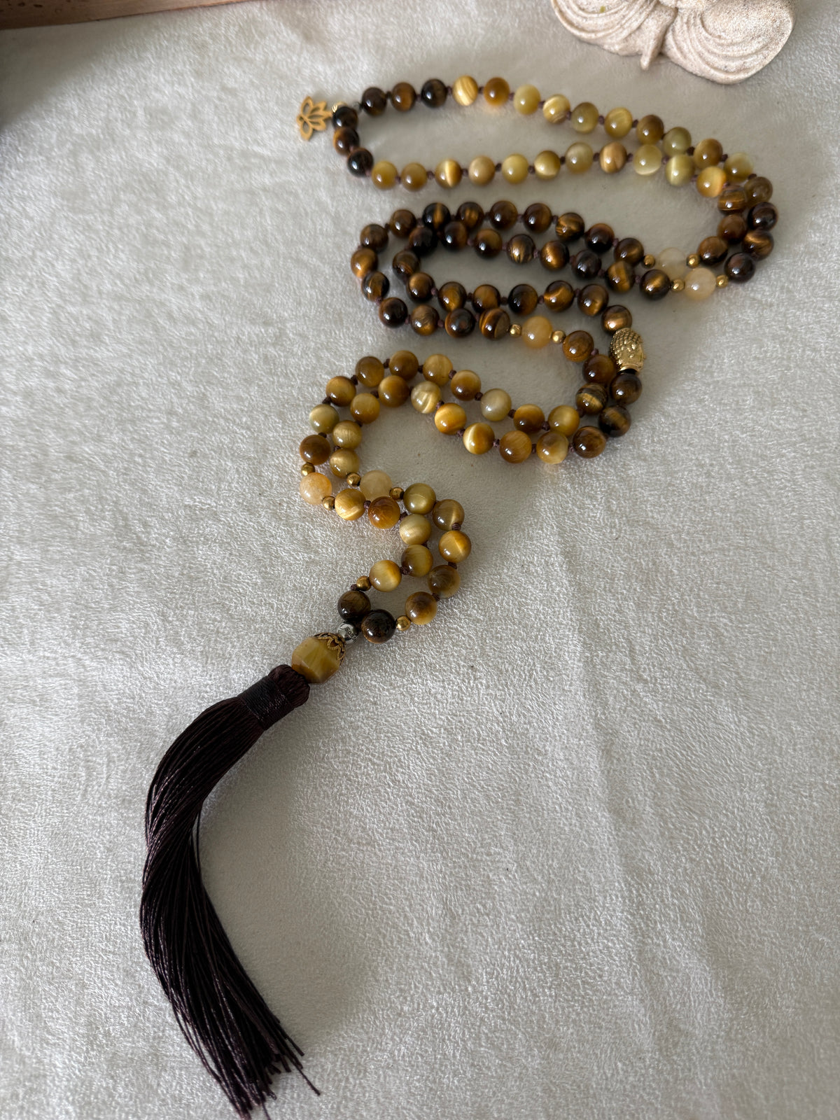 Handmade 108-bead mala necklace with tiger's eye and yellow jade, featuring a Lotus and Buddha charm pendant, designed for grounding, clarity, and centering.