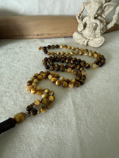 Handmade 108-bead mala necklace with tiger's eye and yellow jade, featuring a Lotus and Buddha charm pendant, designed for grounding, clarity, and centering.