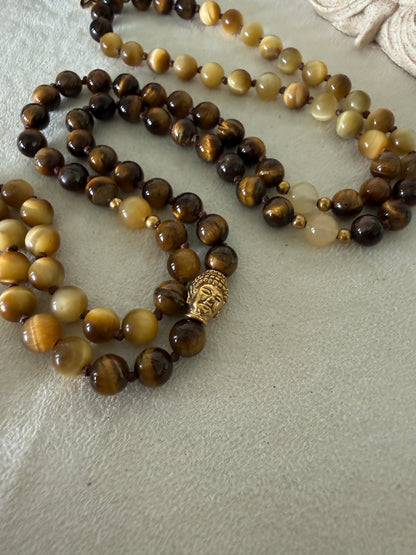 Handmade 108-bead mala necklace with tiger's eye and yellow jade, featuring a Lotus and Buddha charm pendant, designed for grounding, clarity, and centering.