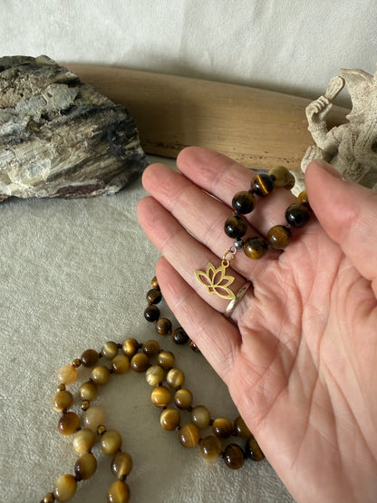 Handmade 108-bead mala necklace with tiger's eye and yellow jade, featuring a Lotus and Buddha charm pendant, designed for grounding, clarity, and centering.