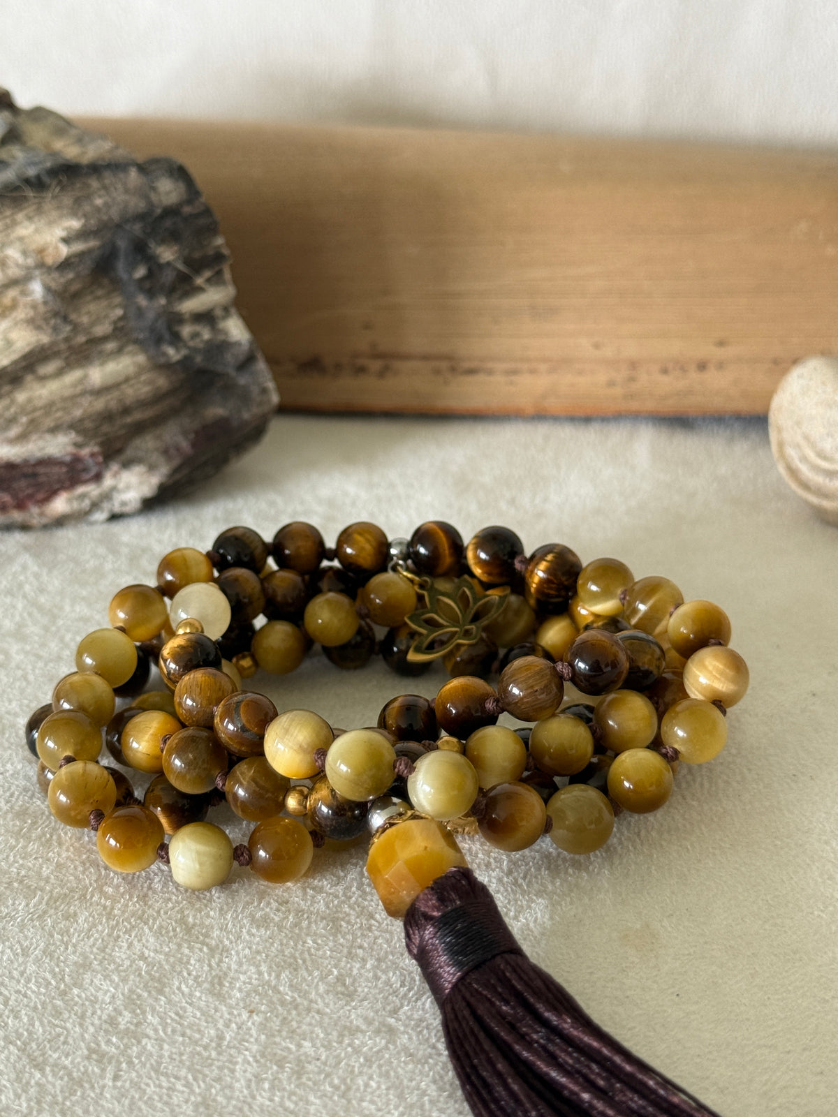 Handmade 108-bead mala necklace with tiger's eye and yellow jade, featuring a Lotus and Buddha charm pendant, designed for grounding, clarity, and centering.