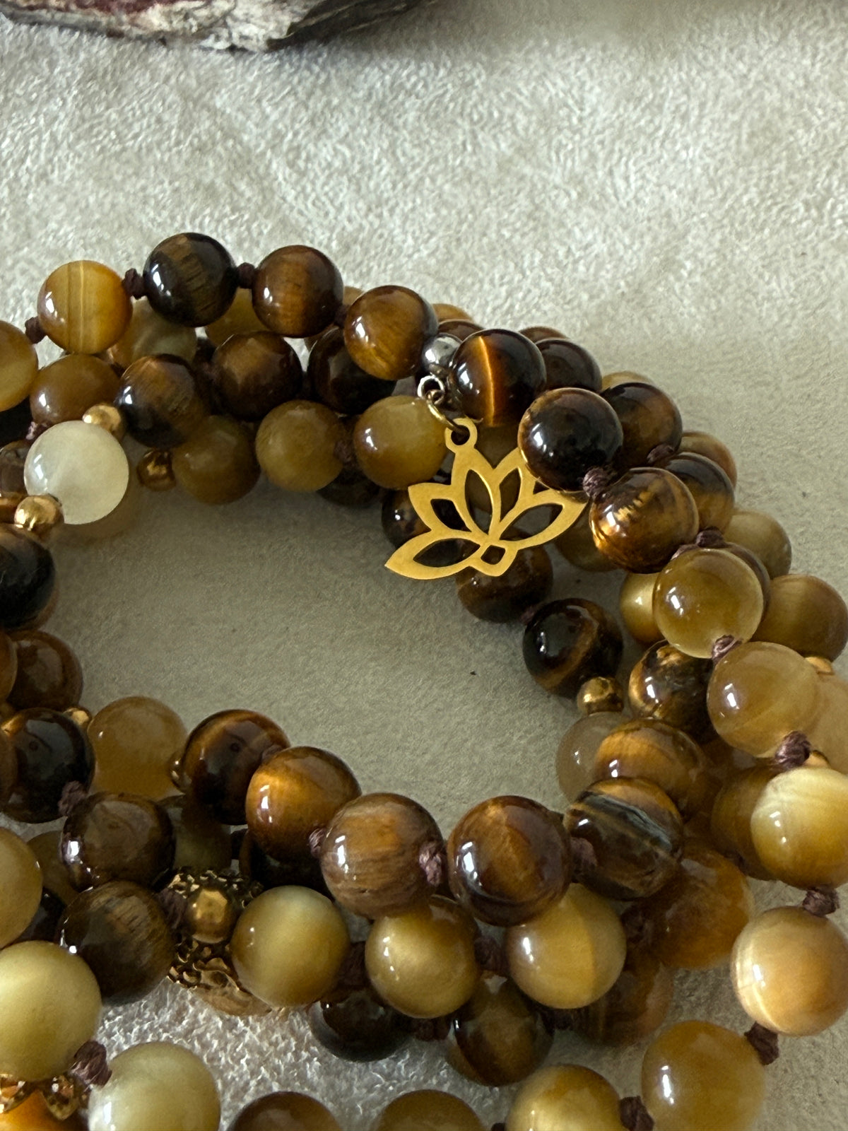 Handmade 108-bead mala necklace with tiger's eye and yellow jade, featuring a Lotus and Buddha charm pendant, designed for grounding, clarity, and centering.