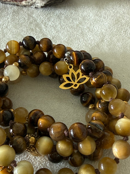 Handmade 108-bead mala necklace with tiger's eye and yellow jade, featuring a Lotus and Buddha charm pendant, designed for grounding, clarity, and centering.