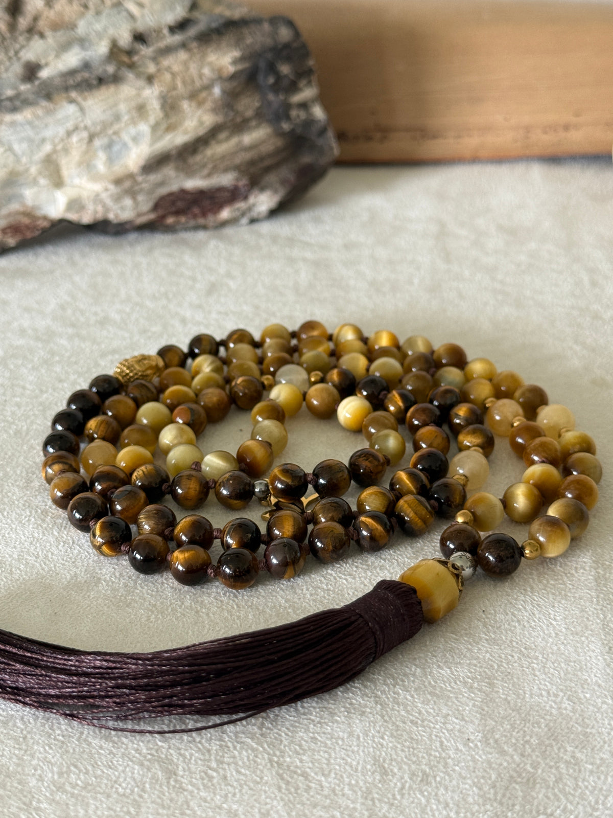 Handmade 108-bead mala necklace with tiger's eye and yellow jade, featuring a Lotus and Buddha charm pendant, designed for grounding, clarity, and centering.